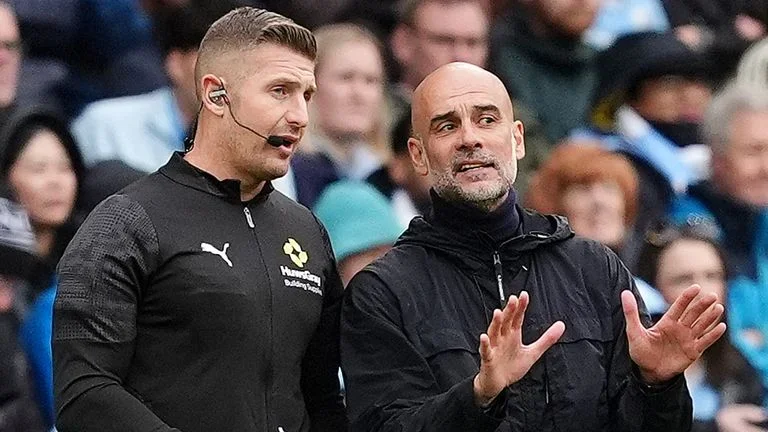 Manchester City manager Pep Guardiola (right) speaks to fourth official Robert Jones